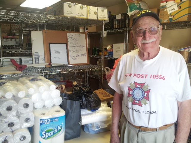 A happy old man takes a picture inside the soup kitchen storage room.