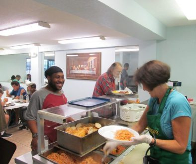 A homeless charity volunteer is enjoying serving food to the homeless people.
