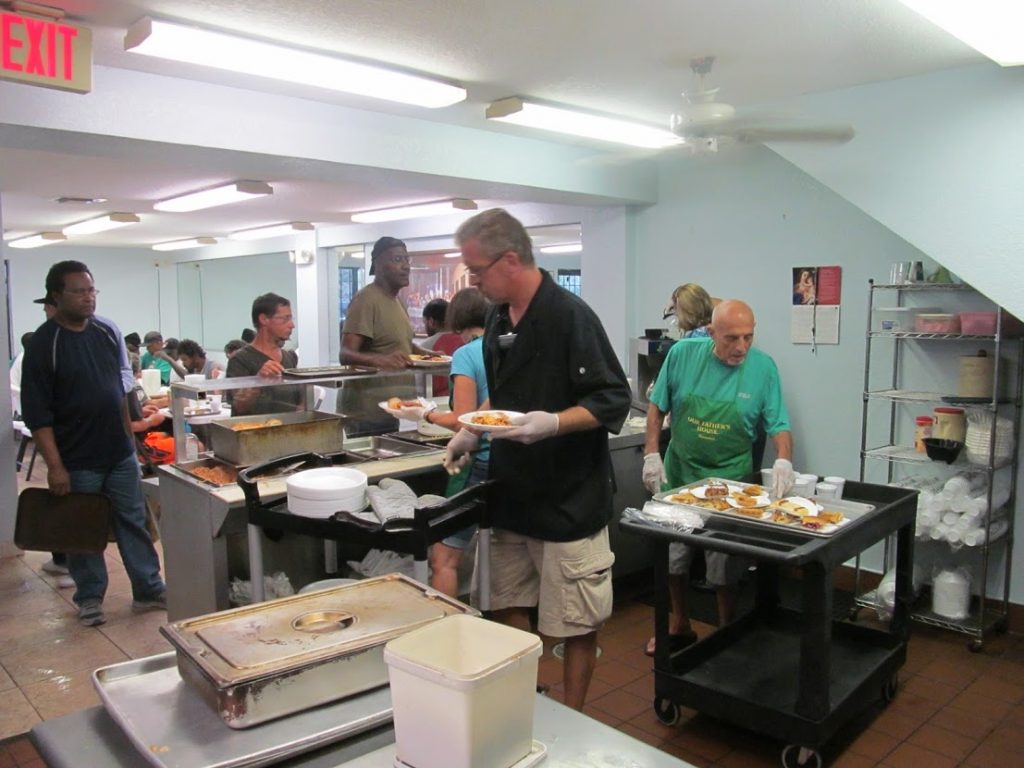 Homeless charity volunteers are serving food to the homeless people.