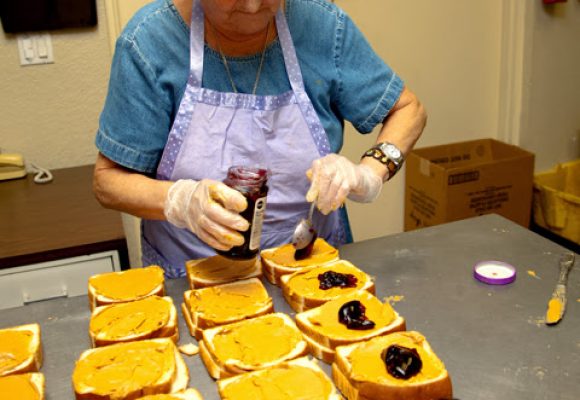 A homeless charity volunteer old woman makes sandwiches for feeding the homeless people.