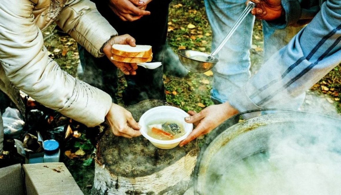 Someone giving soup and bread to a homeless person.