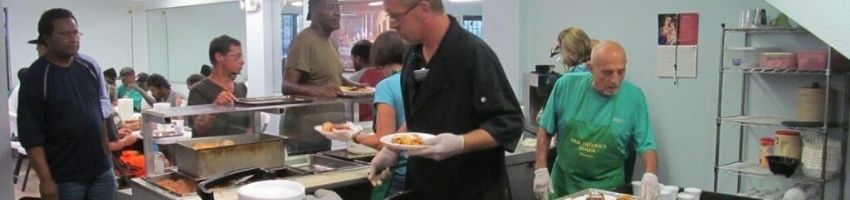 A soup kitchen volunteer serving food to the homeless.