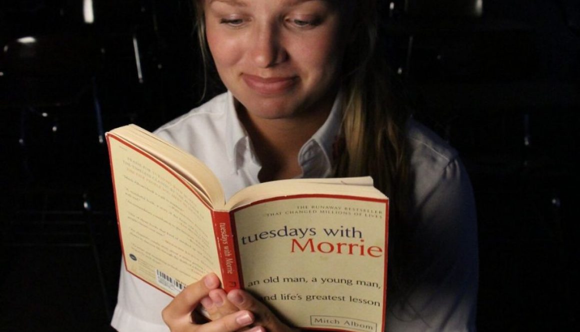 A woman reading Tuesdays with Morrie by Mitch Albom.