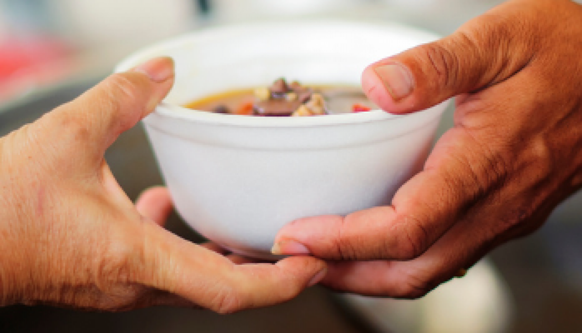 A picture of a hand that giving a soup to people during charity event