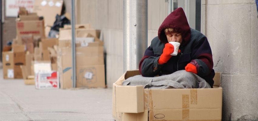 A homeless man sitting on the sidewalk.