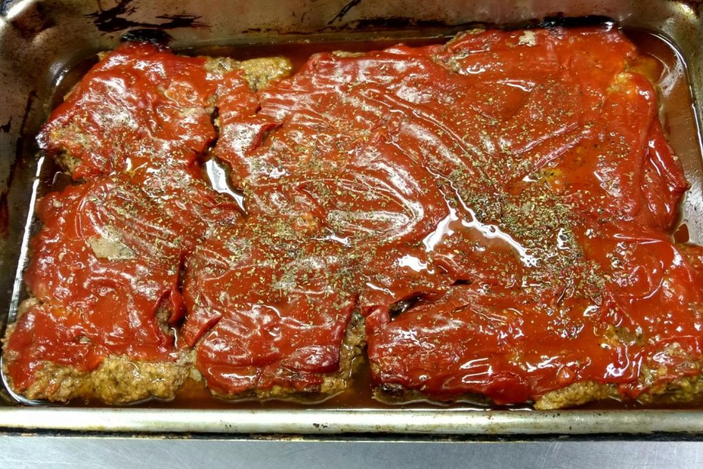 Chicken parmesan being served to hungry people at the soup kitchen.