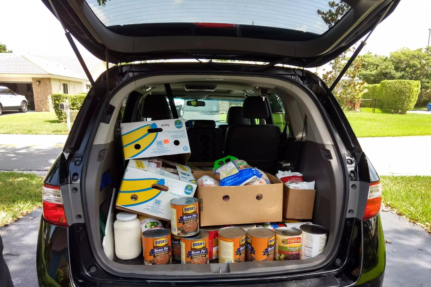 Food donations placed in boxes in the trunk of a car.