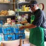 A soup kitchen volunteer loads cases of water into the pantry.