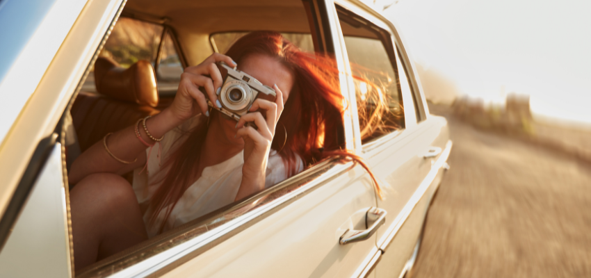 A woman taking pictures while on a road trip.