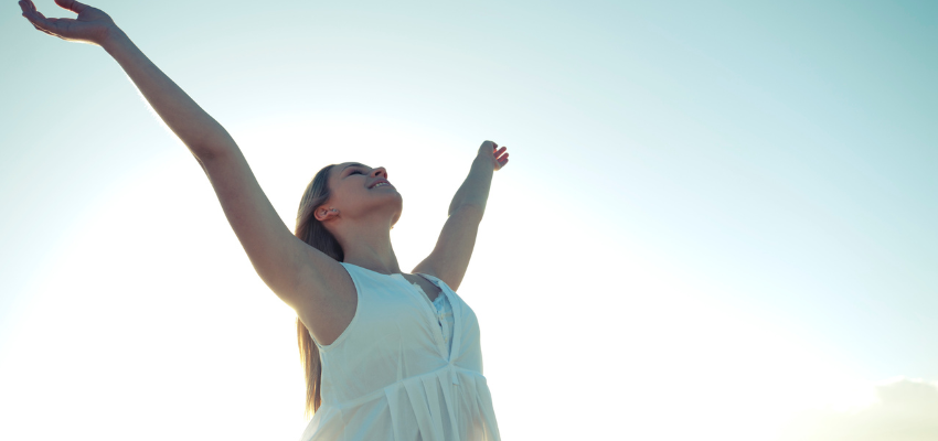 A woman happily raising her arms at the sky.