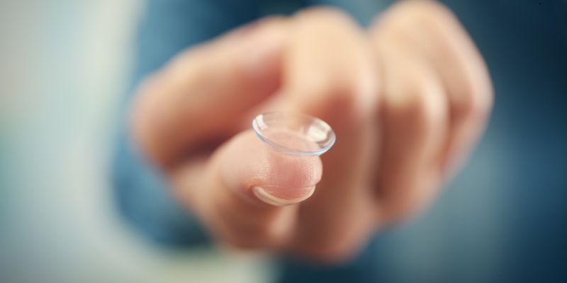 The woman is holding contact lenses.
