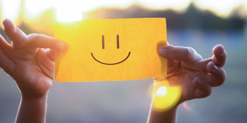 A person posting a smiley note to cheer others happiness.
