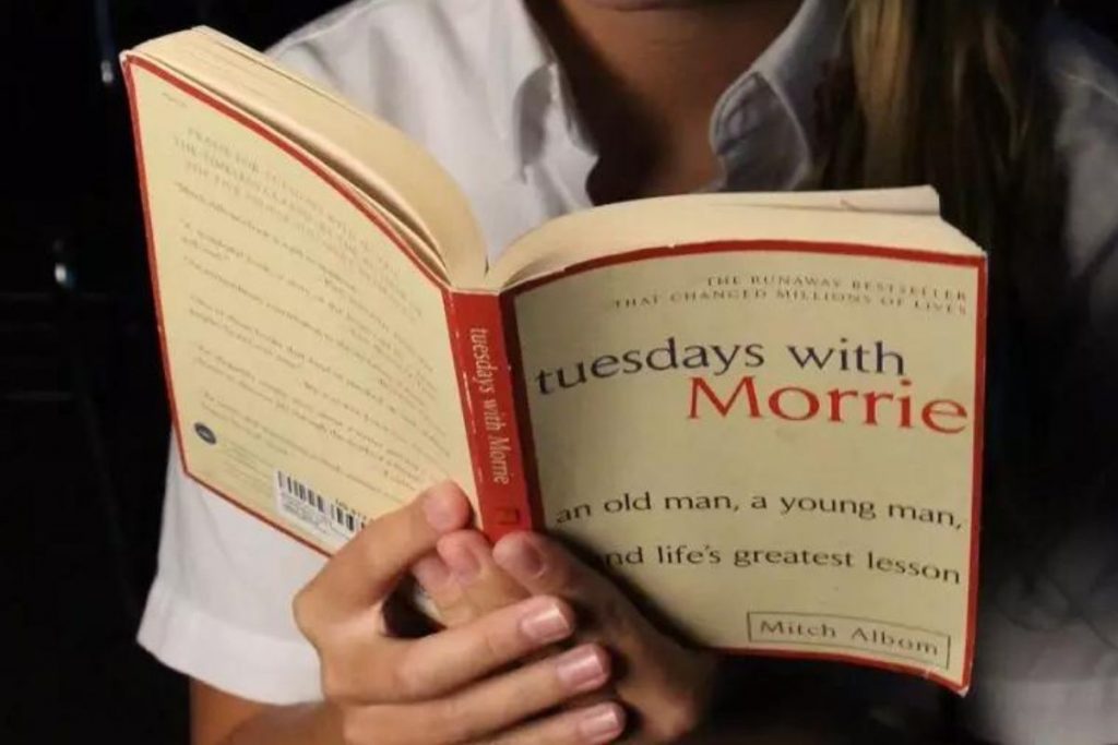 The person is reading the book of Tuesdays with Morrie.
