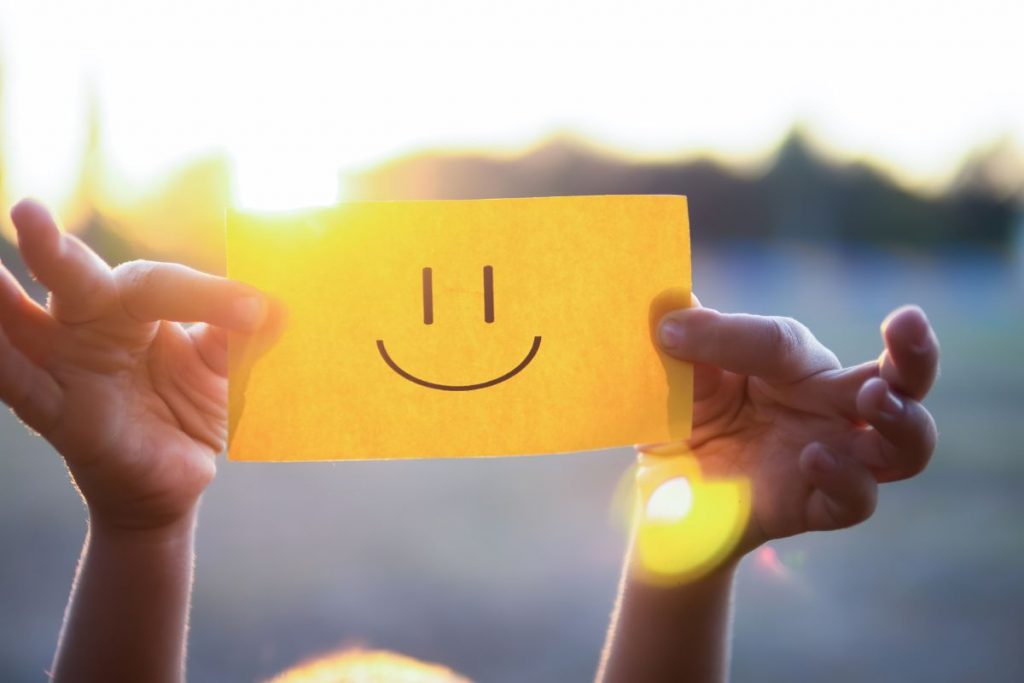 The person is holding smiley sticky notes to remind someone to stay positive.