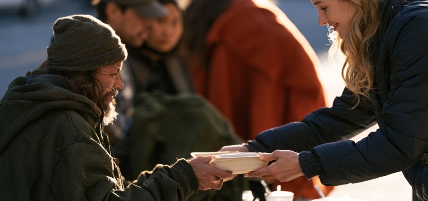 Woman offering food to a smiling man in need, embodying quotes about making a difference.