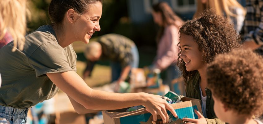 Volunteer helping a child with donations, inspired by quotes about making a difference.
