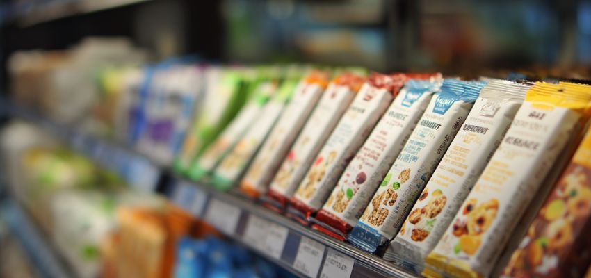 A row of assorted granola and snack bars displayed in a grocery store, one of the surprising things you can buy with food stamps.
