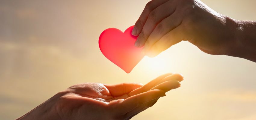 Hands exchanging a symbolic heart at sunrise, representing compassion and support inspired by the most requested items for homeless individuals.