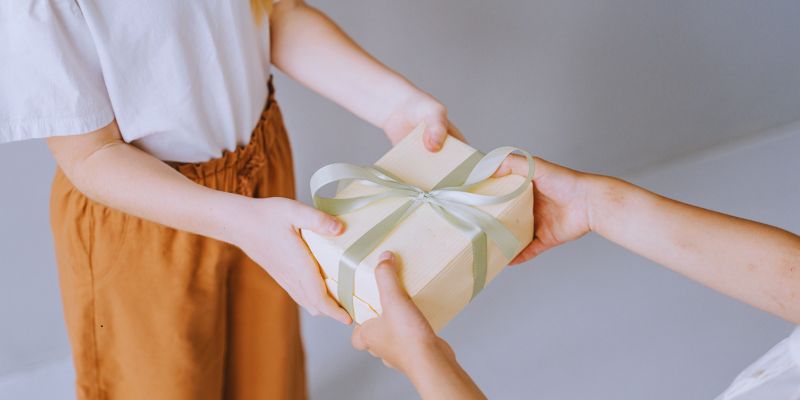 community-service-quotes2 Two people exchanging a gift box wrapped with a ribbon, representing the spirit of kindness and community service quotes.
