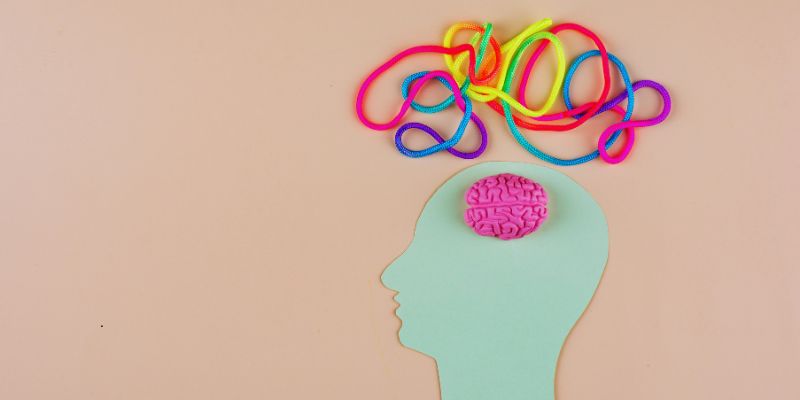 Neurodivergent brain represented by a light blue head silhouette with a small pink brain and a chaotic tangle of colorful wires above, symbolizing complex and unique thinking patterns.
